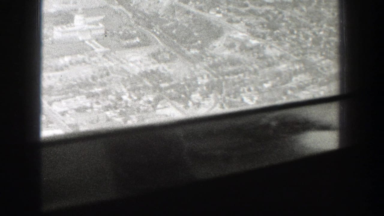1939 Wyoming home-movie frame showing a city from above through the dark structure of an airplane window.
