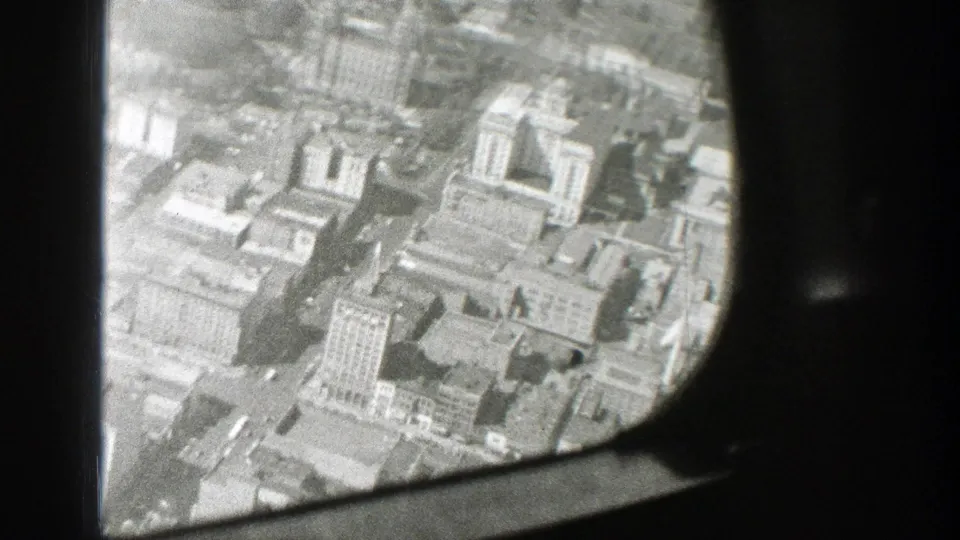 Aerial view of a built-up city area from an airplane, with the window structure cutting across the frame.