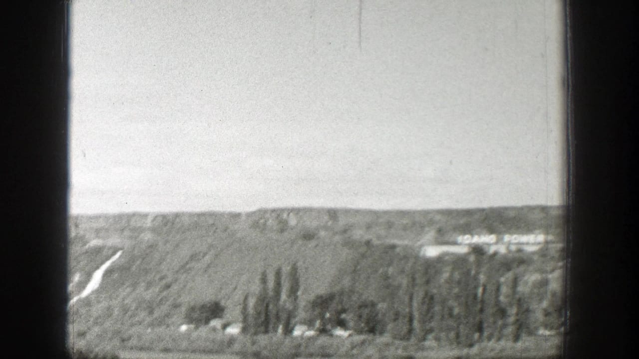 1939 Wyoming landscape frame showing a sloped hillside, a pale road or hillside cut, trees, and distant Idaho Power lettering.