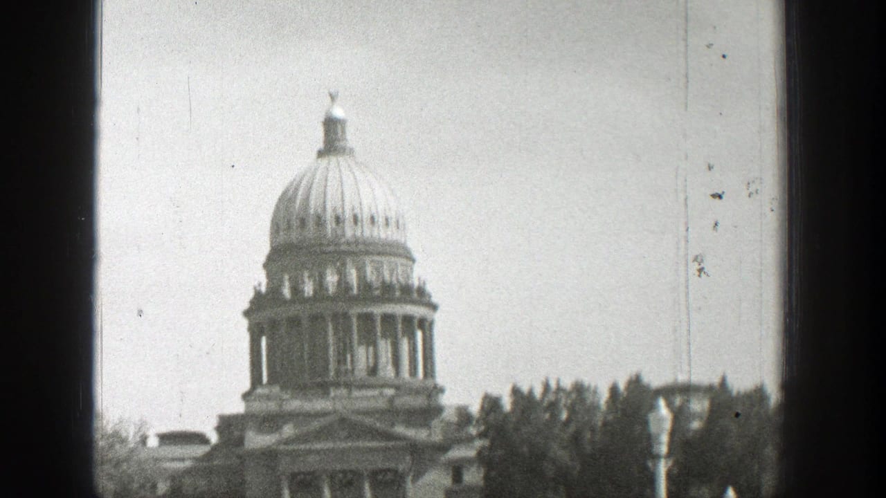Domed classical government building seen beyond trees.