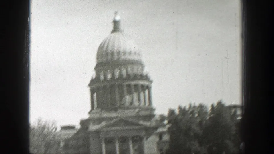 Black-and-white home-movie frame of the likely Wyoming State Capitol dome and facade, softened by focus drift and visible film wear.