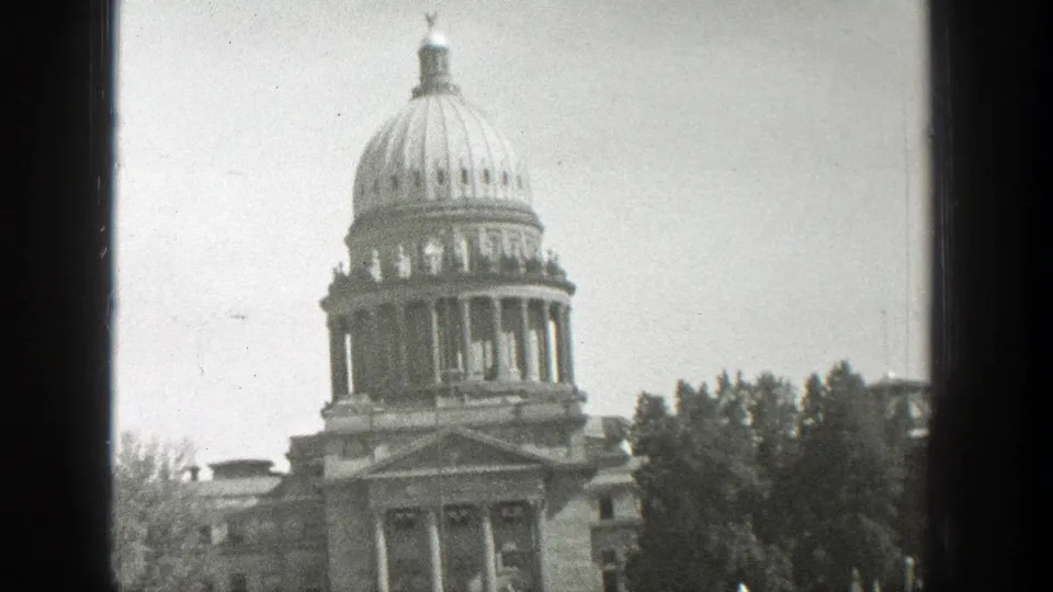 1939 black-and-white 8mm view of the Wyoming State Capitol, framed by a dark window edge with trees beside the building.