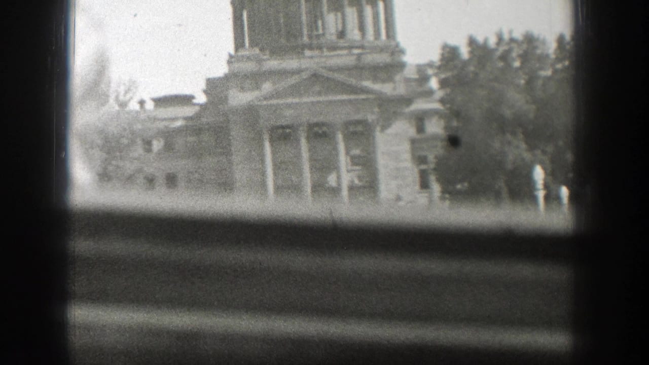 Partial view of a domed capitol building through window panes.
