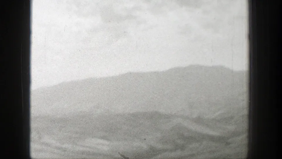 1939 Wyoming train-window view showing arid hills and distant mountain ridges through a dark window frame.