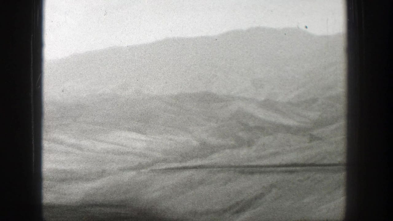 1939 Wyoming footage frames a barren, rolling landscape and distant ridge from inside a moving train.