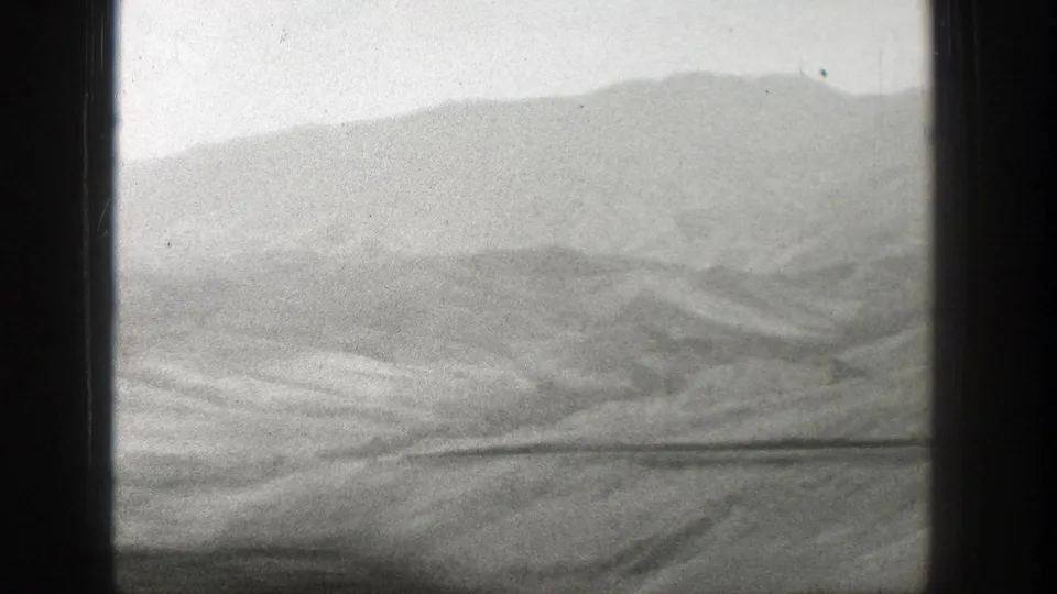 1939 Wyoming footage frames a barren, rolling landscape and distant ridge from inside a moving train.