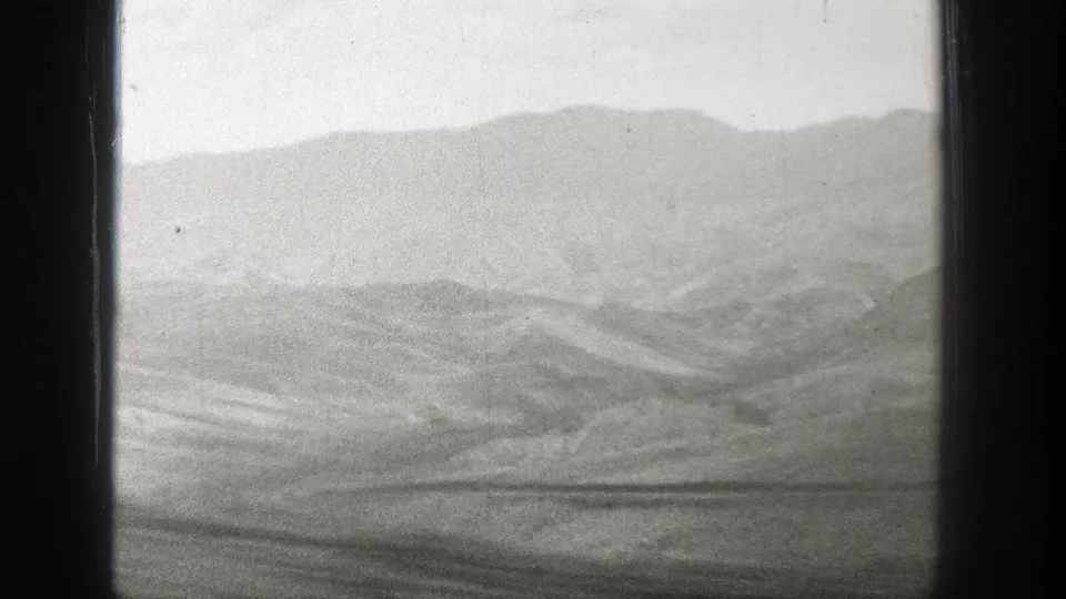 A passenger view across Wyoming’s dry hills and distant mountains, softened by 8mm grain and train motion.
