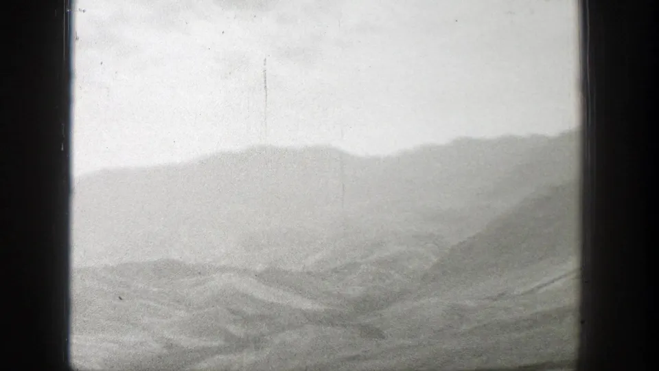1939 Wyoming home-movie frame showing layered mist-covered mountains beneath an overcast sky with visible 8mm gate edges.