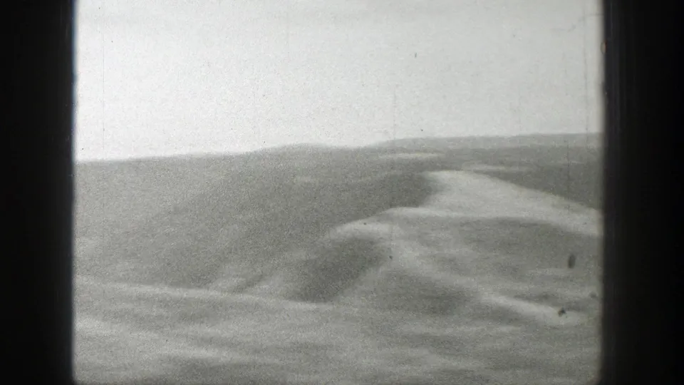 Passing 1939 Wyoming landscape frame with rolling hillside, distant mist, and dark 8mm film-frame edges.