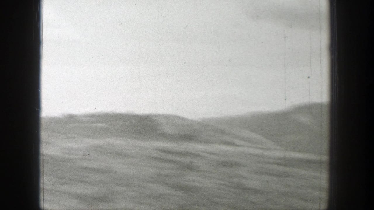 Empty rolling landscape with distant hazy mountains and dark film borders.