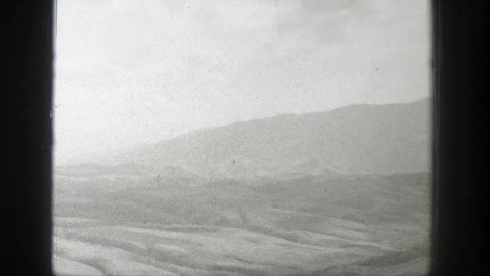 Black-and-white 1939 Wyoming frame showing open dry ground and a broad distant hillside through a soft 8mm image.