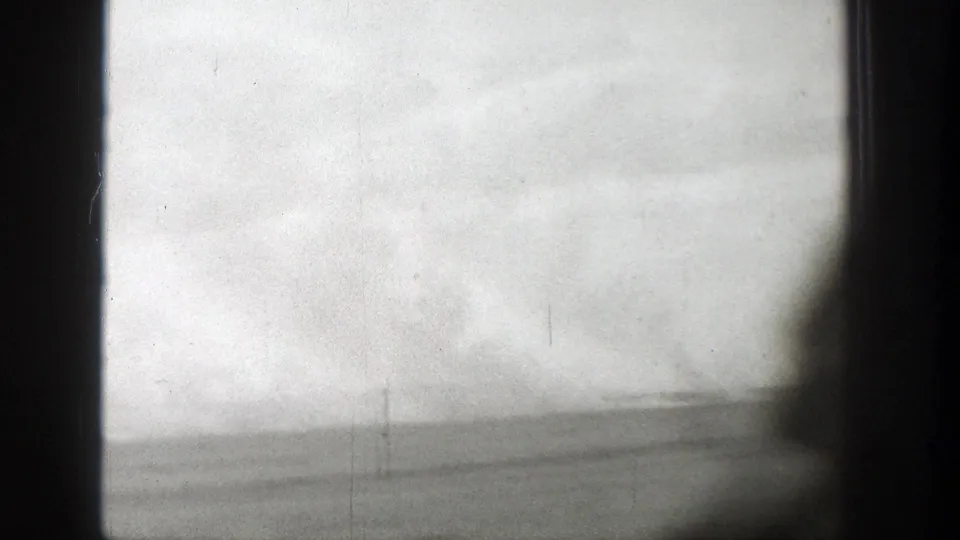 1939 Wyoming travel footage with a low desert horizon, pale sky, dark window frame, and blurred foreground silhouette.