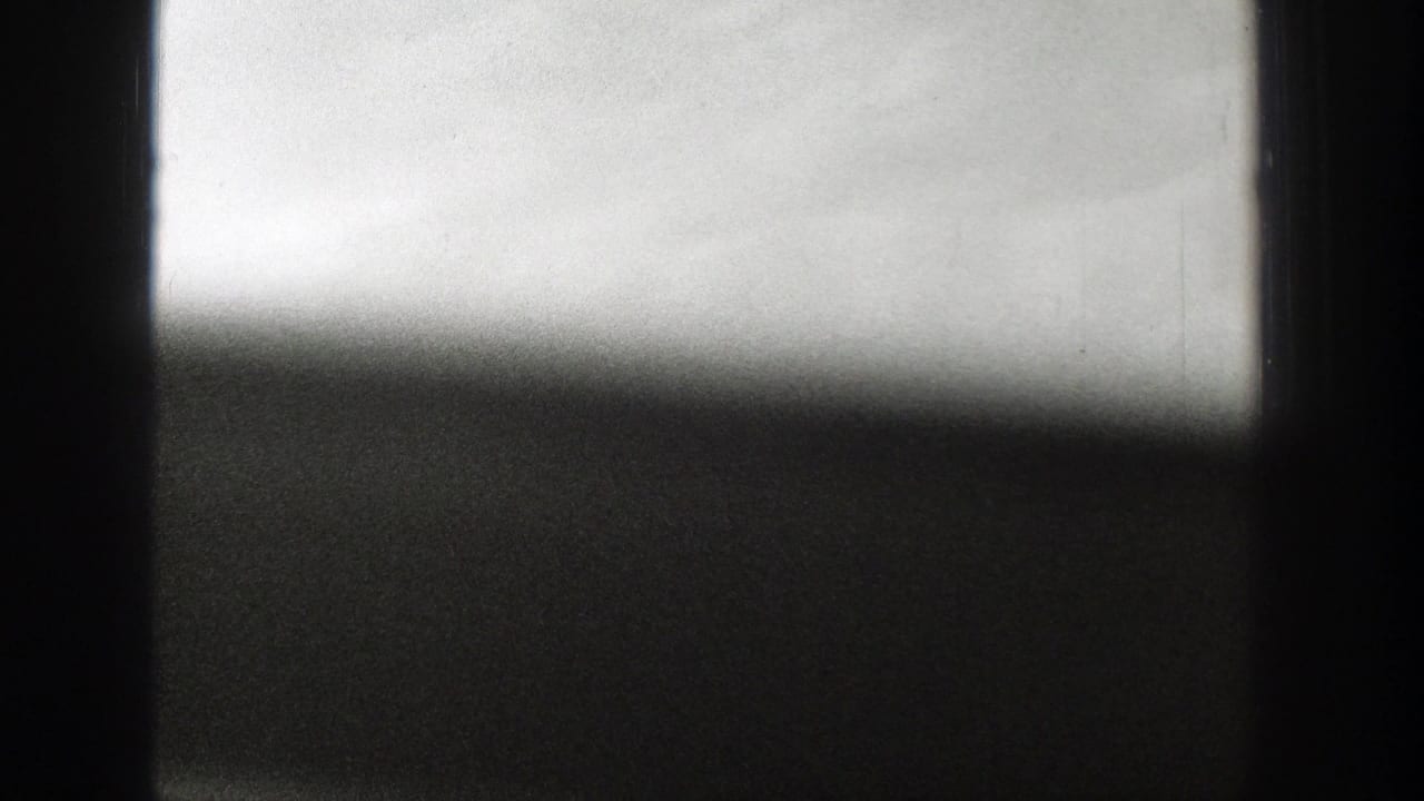 1939 Wyoming 8mm frame showing a smoky rural horizon through dark foreground edges and a bright, washed sky.