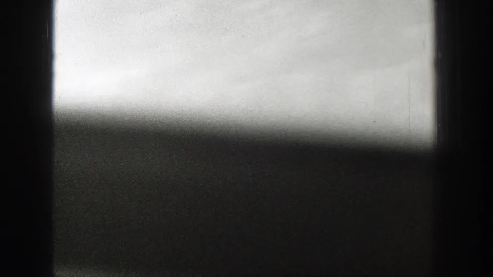 1939 Wyoming 8mm frame showing a smoky rural horizon through dark foreground edges and a bright, washed sky.