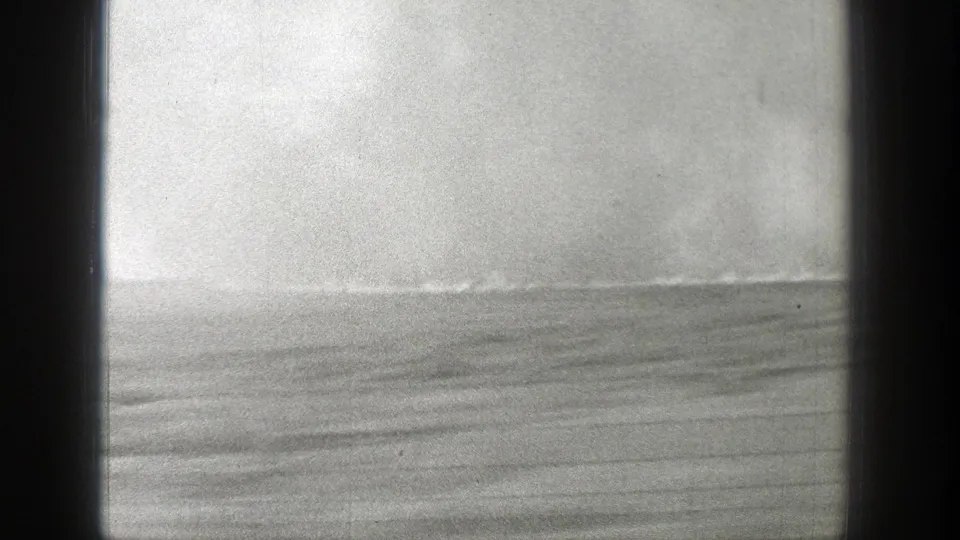 1939 Wyoming home-movie frame with a low field horizon, smoke or haze, and dark gate-like edges.