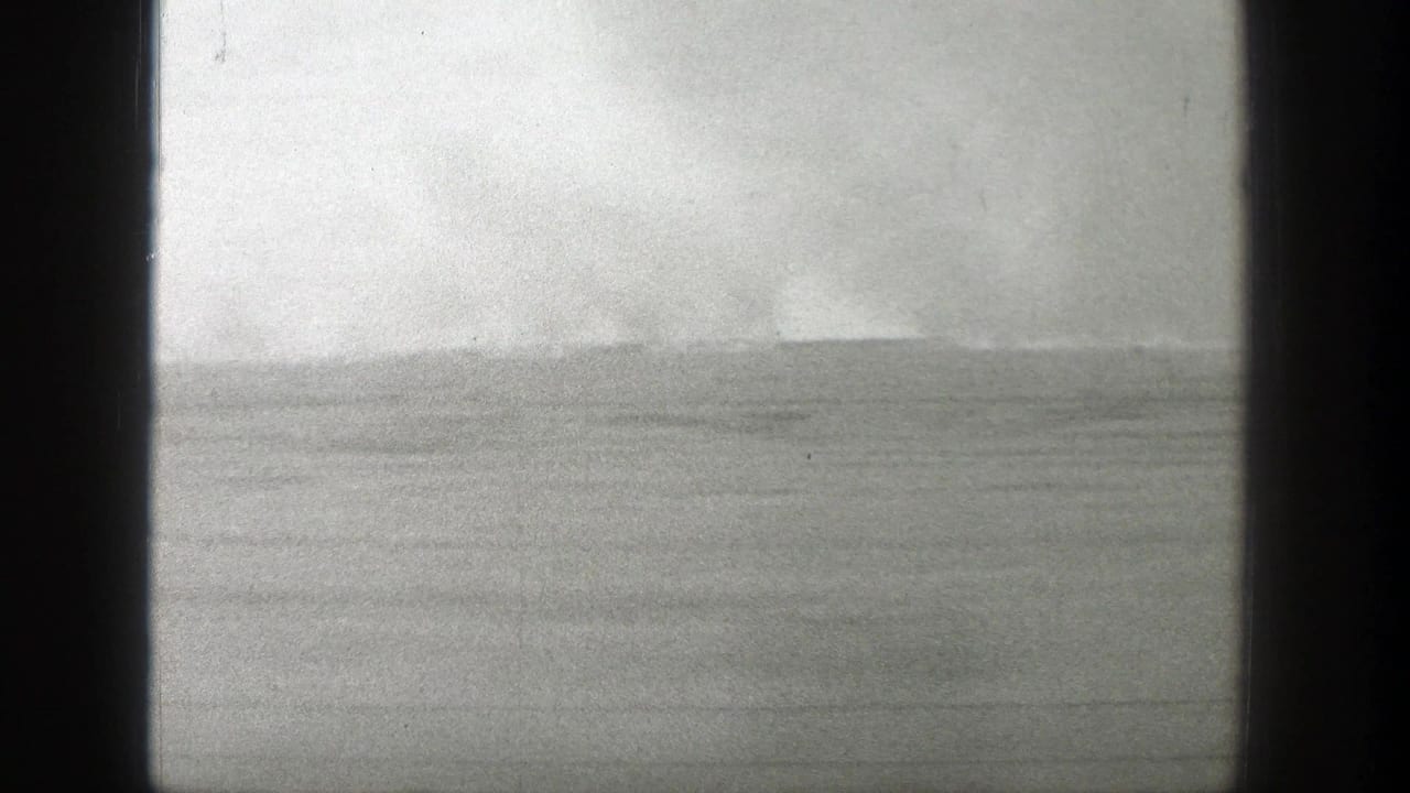 Flat landscape seen through dark vertical borders under a hazy overcast sky.