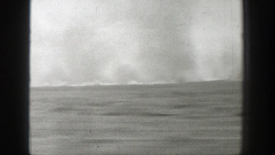 The moving 8mm view shows flat Wyoming terrain and a hazy, turbulent sky through dark window-like borders.