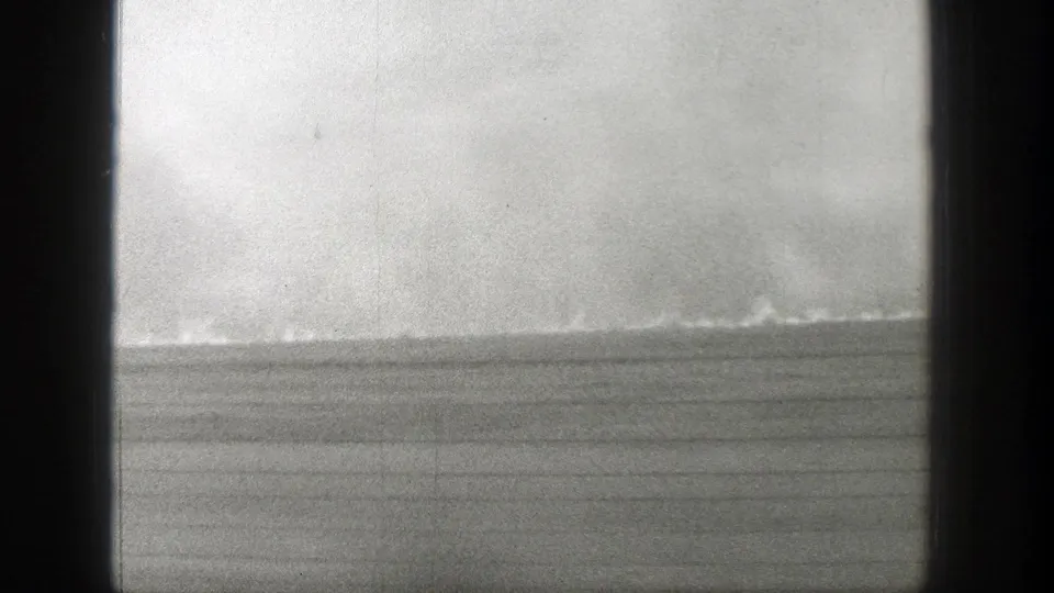 A late-1930s Wyoming travel frame shows a broad plain and faint weather or dust activity along the horizon.