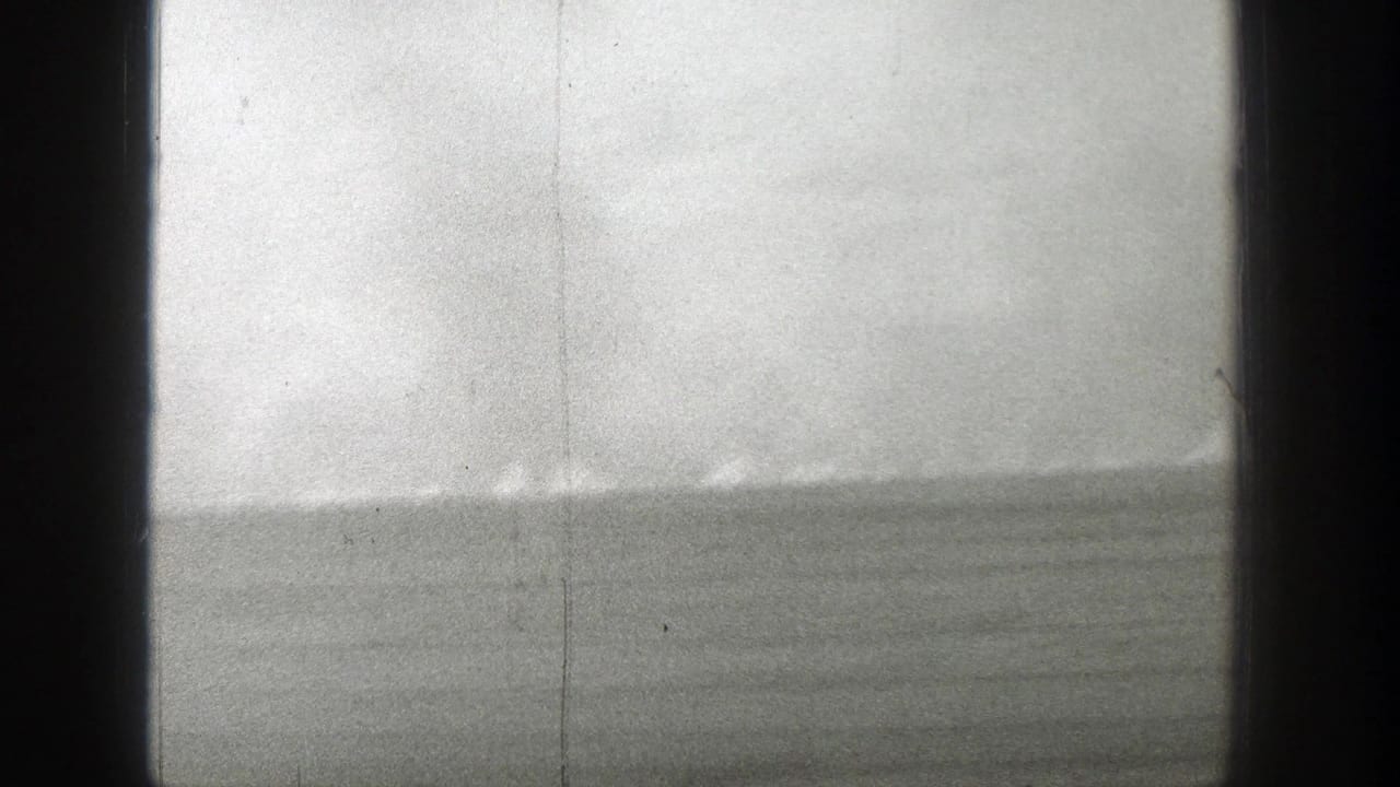 Distant fire or smoke line across an open plain seen between dark vertical frame edges.
