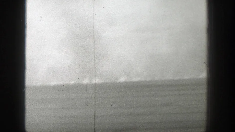1939 Wyoming 8mm frame showing a hazy open plain with a distant grass fire line and dark vertical framing at the sides.