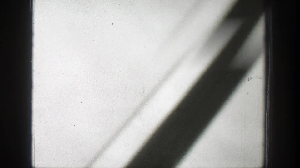 1939 Wyoming 8mm frame with dark vertical bars, diagonal shadows, pale sky, and soft smoke haze.