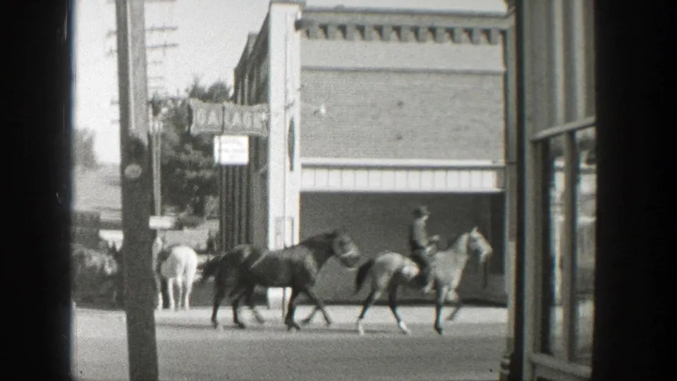 Near the end of the clip, the rider leads two horses past the storefront as other horses and a few people remain near the curb in Wyoming.