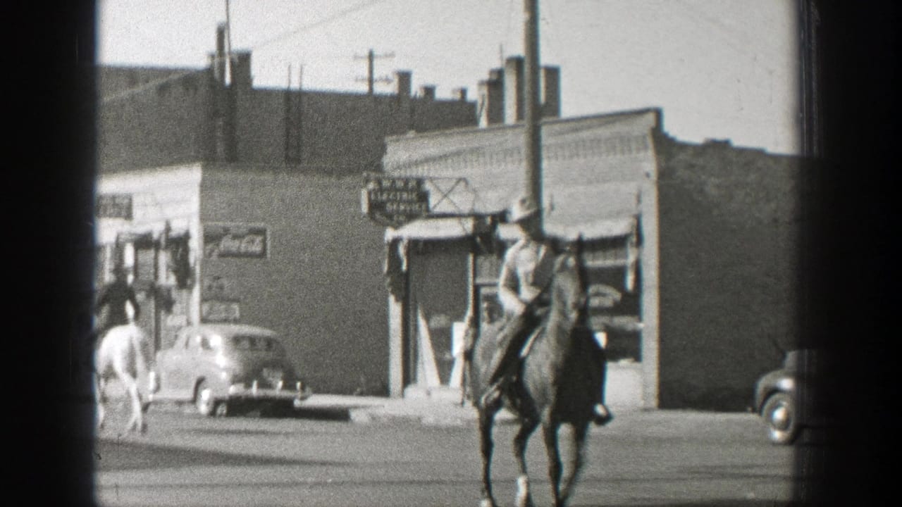 In 1939 Wyoming, a cowboy rides a horse through a small town street with parked automobiles and storefront signage nearby.