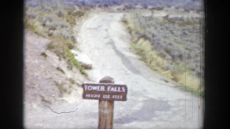 Wooden Tower Falls sign marked 132 feet beside a pale dirt path in Wyoming archival 8mm footage.