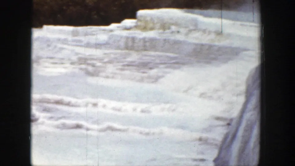 1939 Wyoming 8mm frame showing pale frozen terraces or mineral ledges bordered by dark winter trees.