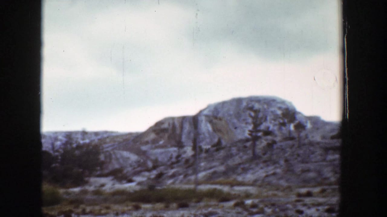 Rocky Wyoming hillside seen through dark vertical frame edges under a pale sky.