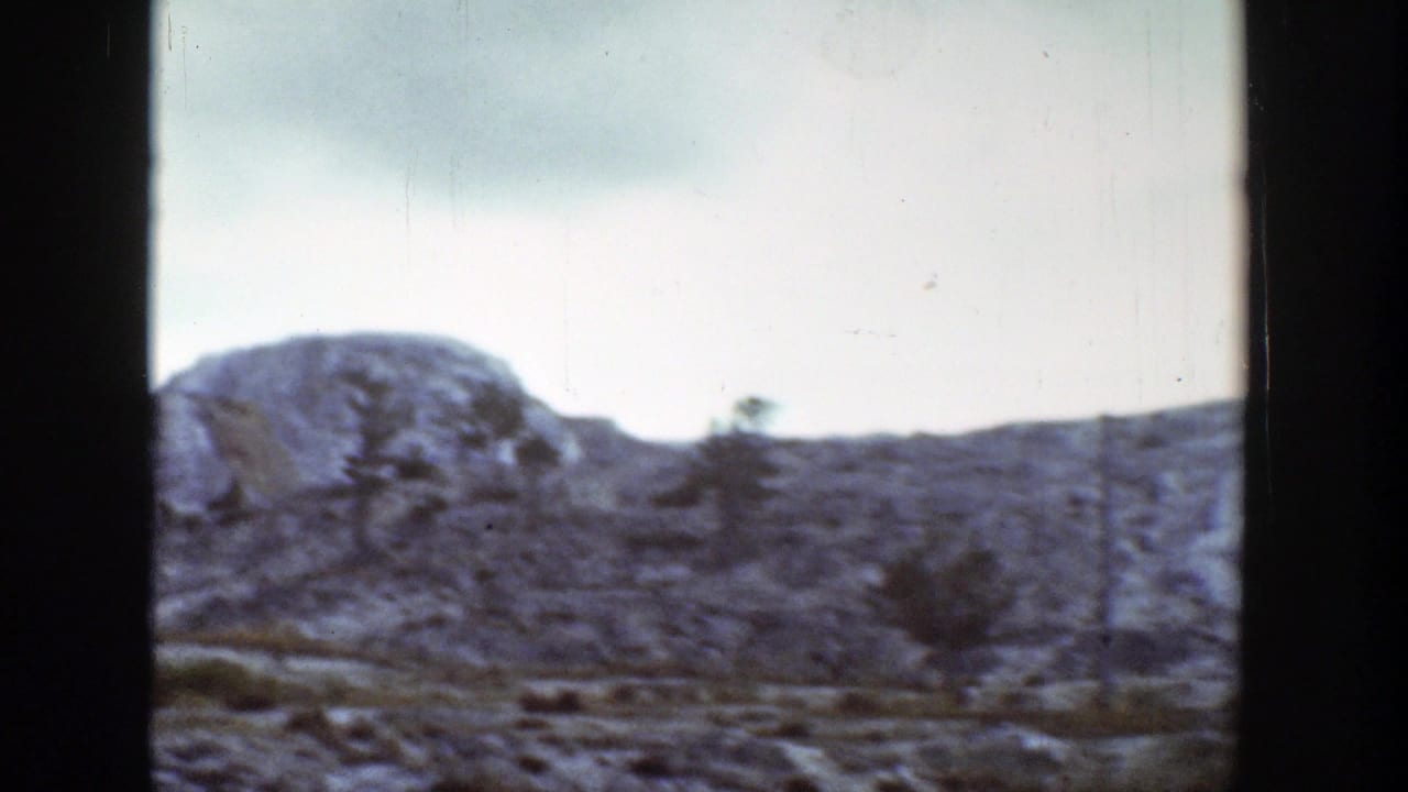 Rugged Wyoming hill and scattered small trees appear in a soft 1939 8mm home-movie frame.