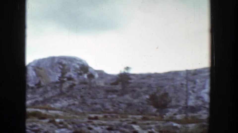 Rugged Wyoming hill and scattered small trees appear in a soft 1939 8mm home-movie frame.