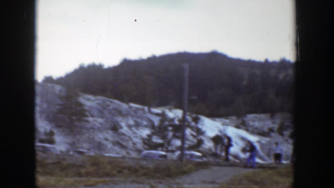 1939 Wyoming tourist scene with classic cars near a dirt path and pale layered rock formations.