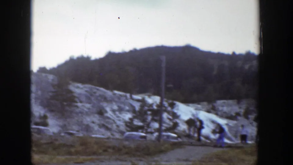 1939 Wyoming tourist scene with classic cars near a dirt path and pale layered rock formations.