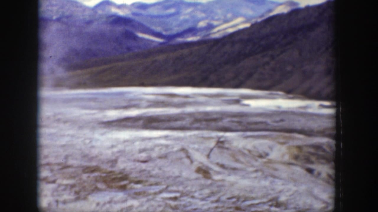 1939 Wyoming home-movie frame showing a pale dry basin, dark hills, and distant mountains with soft 8mm color and frame edges.