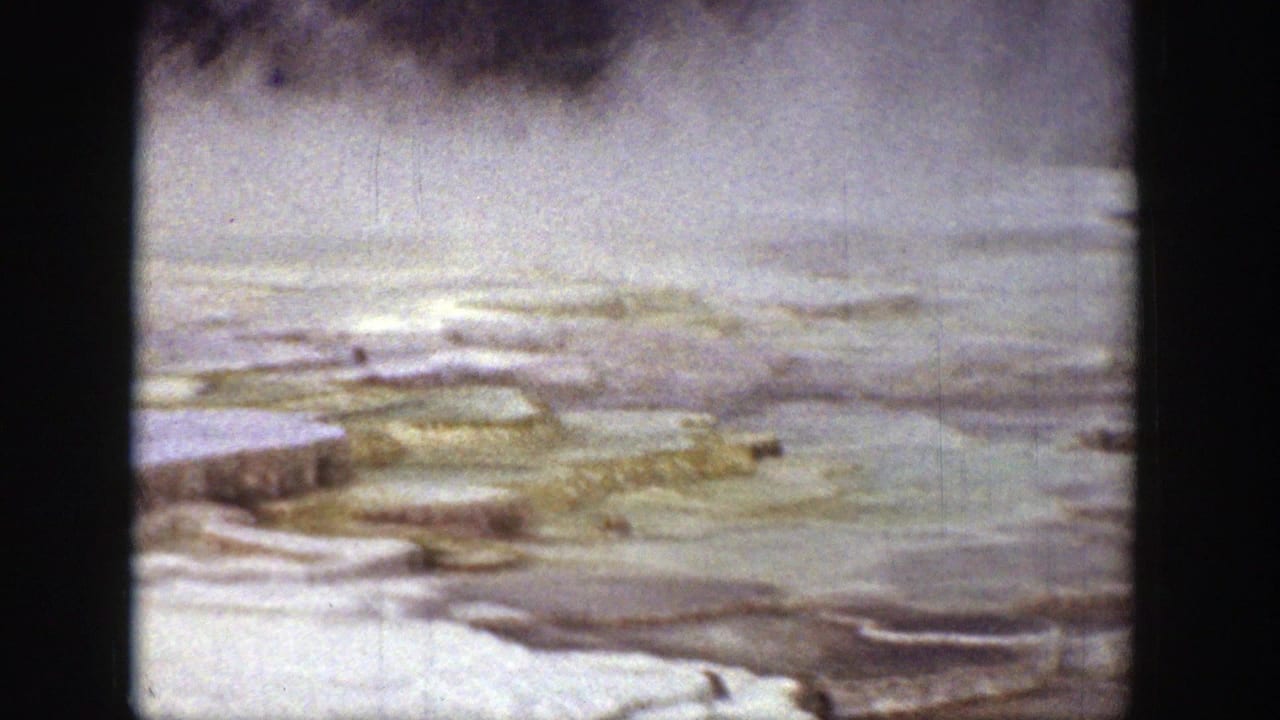 Steaming mineral terraces and pale rock ledges viewed through an 8mm frame.
