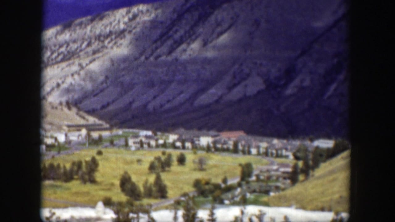 Buildings and trees at the base of steep mountain slopes.