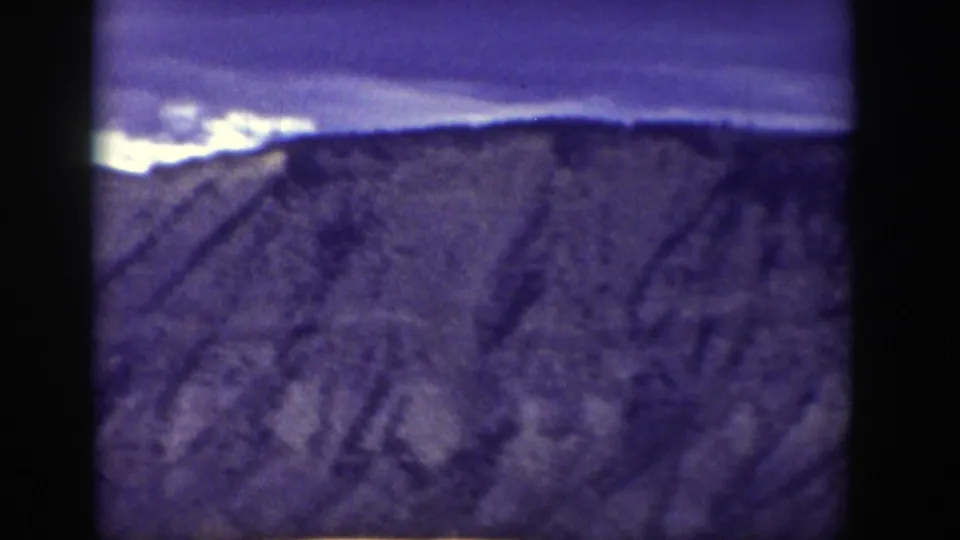 Early frame from the Wyoming 1939 home movie showing a distant mountain ridge under a dark sky, with the image soft and heavily shadowed.