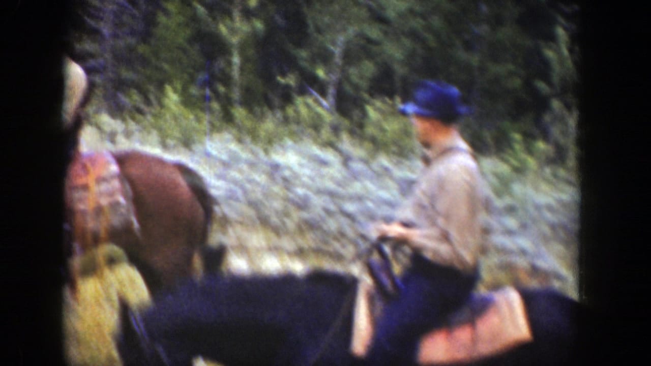 1939 Wyoming frame with a blue-capped rider on horseback near other riders, backed by trees and rough mountain terrain.