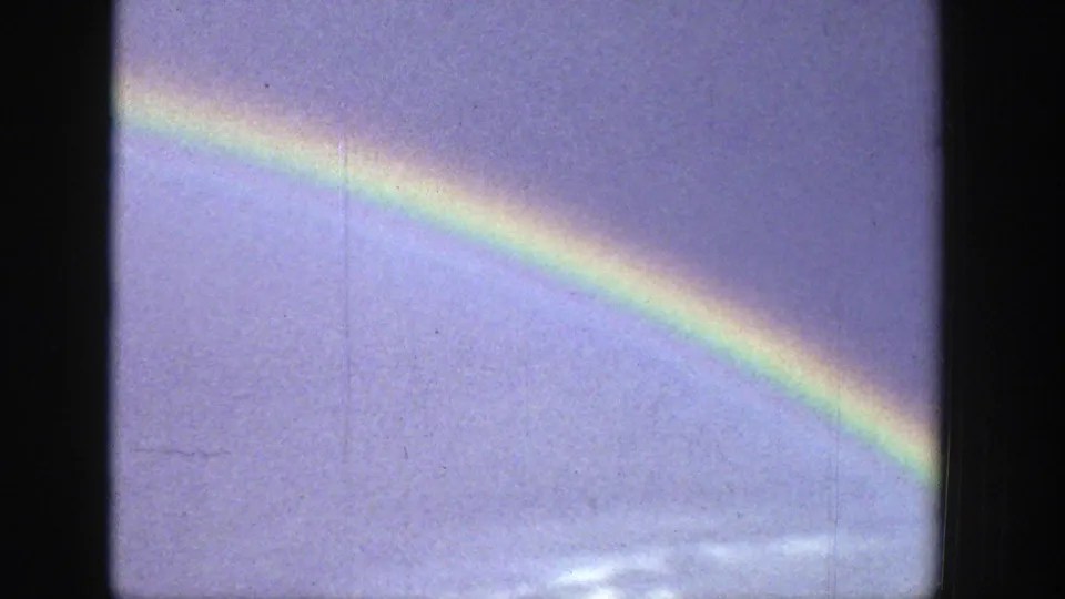 A rainbow arcs across a cloudy sky in 1939 Wyoming 8mm home-movie footage, with soft color and visible film borders.