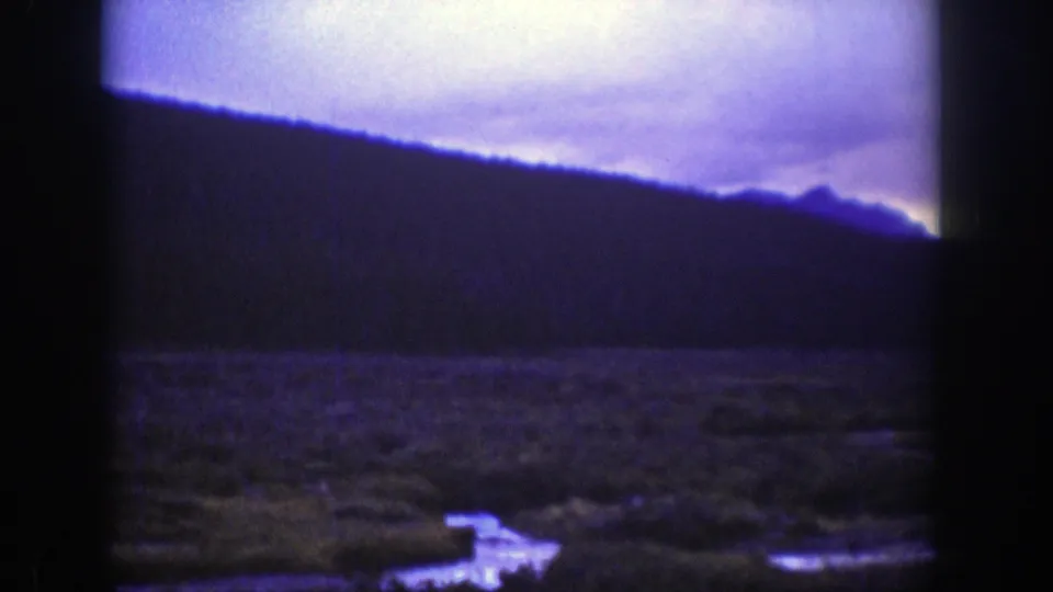1939 Wyoming 8mm frame showing a dark ridge, open wetland, and pale sky with heavy gate edges and color shift.
