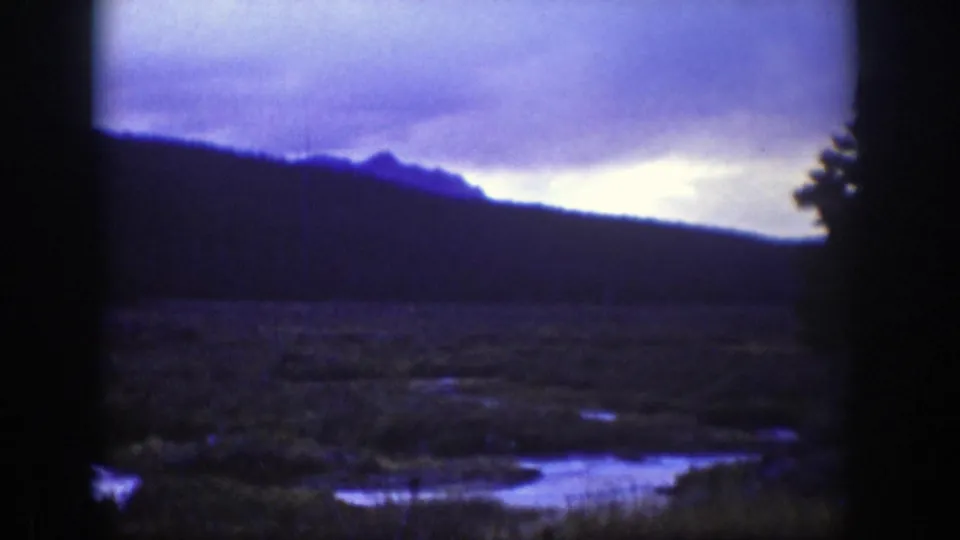 1939 Wyoming landscape frame with ridge line, open meadow or marsh, water channels, and visible 8mm frame borders.