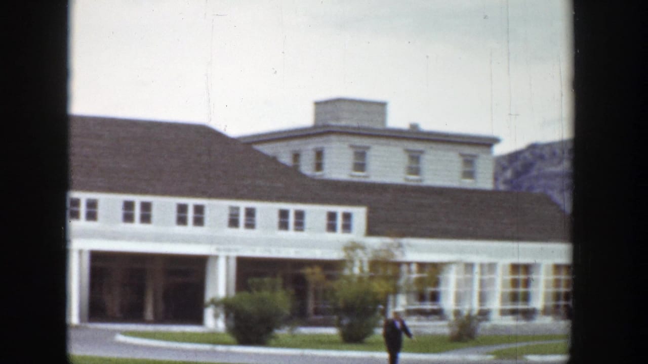 Large white building with covered walkway and a suited man crossing in front.