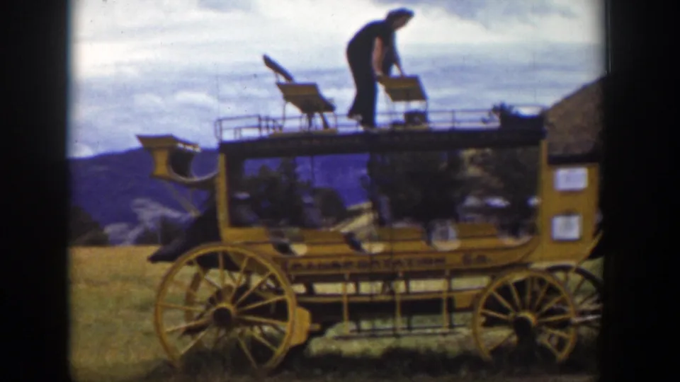 In the Wyoming home-movie scene, the man remains on the carriage roof and appears to handle one of the top bench seats.