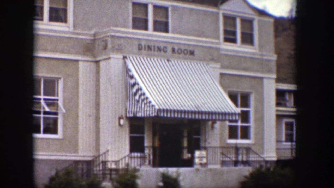 1939 Wyoming exterior view of a dining room building with striped awning, windows, entrance steps, and painted sign.