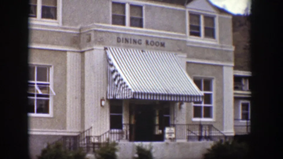1939 Wyoming exterior view of a dining room building with striped awning, windows, entrance steps, and painted sign.