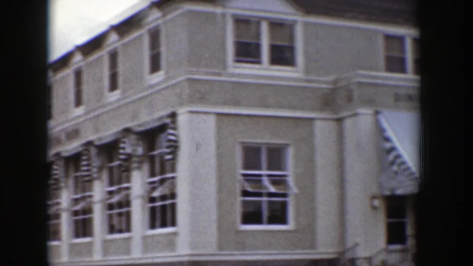 Exterior corner of a Wyoming dining room building, showing multi-pane windows, striped awnings, and pale stucco walls.