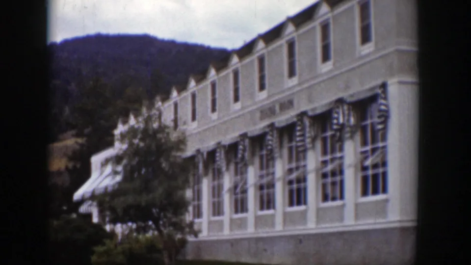 Long exterior view of the dining room building in Wyoming, with repeated windows, striped awnings, shrubs, and hills behind.