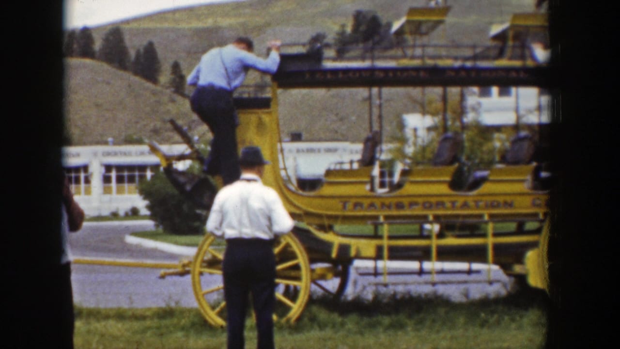 A man descends from the yellow stagecoach in the Wyoming home-movie scene while another adult stands beside the wheel.