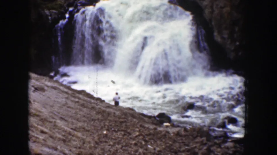 A 1939 Wyoming 8mm frame with the falls dominating the scene and a small observer near the rocky shoreline.